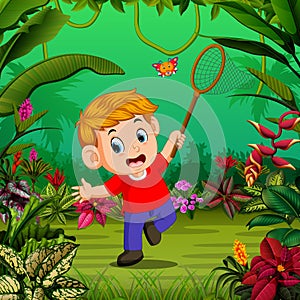 The boy tries to catch a butterfly in the forest