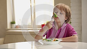 Boy tries to eat a vegetables but dosen`t like it and rejects the food. Healthy food concept. Children and vegetables.