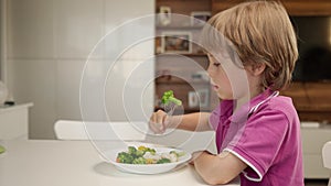 Boy tries to eat a vegetables but dosen`t like it and rejects the food. Healthy food concept. Children and vegetables.