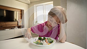 Boy tries to eat a vegetables but dosen`t like it and rejects the food. Healthy food concept. Children and vegetables.