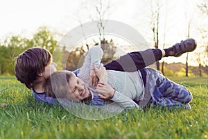 Boy trying to grab and immobilize comrade who wrinkled face attempting to win, friends fighting and playing on meadow.