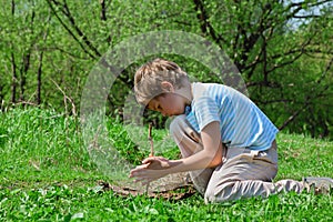 Boy trying to take flame by primitive way by stick