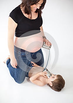 Boy trying to talk to his future brother who is inside the belly of his pregnant mother