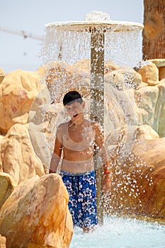 Boy in tunisian aquapark resort under shower