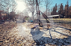 Boy turns on carousel on playground at deep autumn time