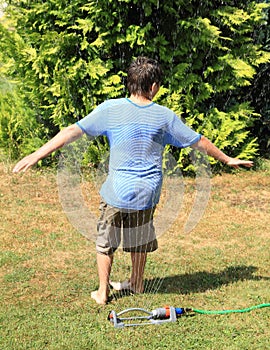 Boy twisting behind sprinkler