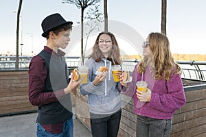 Boy and two girls on city street with burgers and orange juice