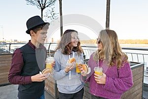 Boy and two girls on city street with burgers and orange juice