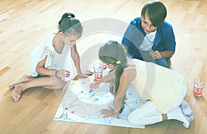 Boy and two girls playing at board game indoors