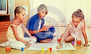 Boy and two girls playing at board game indoors
