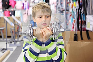 Boy two hands holds metal dumbbell