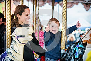 Boy with Two Thumbs Up with Mother on Carousel