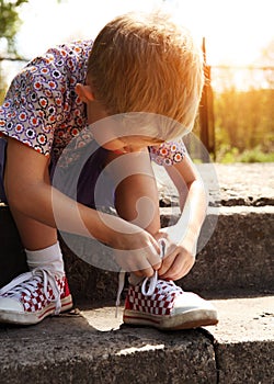 Boy tying the laces on sneakers himself