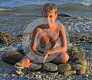 Boy under evening glow on stony beach