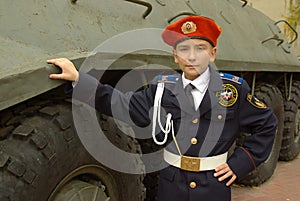 Boy in uniform with an armored troop carrier