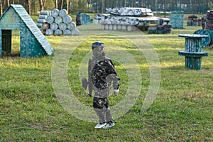 Boy in uniform with paintball gun and helmet on the field. Sport, active lifestyle