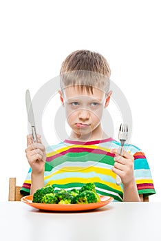 The boy with the unloved food broccoli on a white