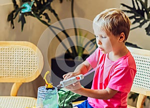 Boy use hot melt glue gun making yourself DIY toys from recycled plastic cup materials. Supporting creativity hand craft