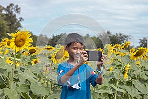 A boy used mobile phone taking a selfie while going to sunflower field.