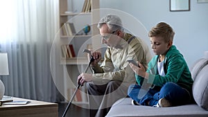 Boy using cell phone, upset granddad sitting aside, internet addiction concept