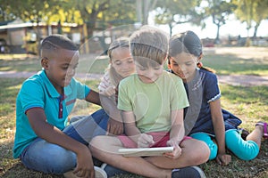 Boy using digital tablet while sitting with friends