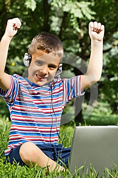 Boy using his laptop outdoor in park on grass