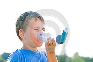 Boy using inhaler for asthma in nature