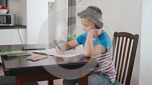 Boy using laptop and headphones for studying at home