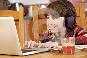 Boy Using Laptop Whilst Eating Breakfast