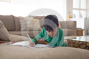 Boy using mobile phone while drawing a sketch on book at home