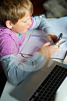 Boy Using Mobile Phone Instead Of Studying In Bedroom