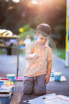 Boy using a paintbrush to paint a sheet of paper