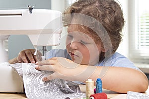 Boy using sewing machine at home to make crafts