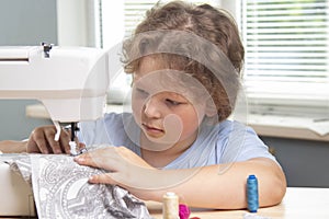 Boy using sewing machine at home to make crafts