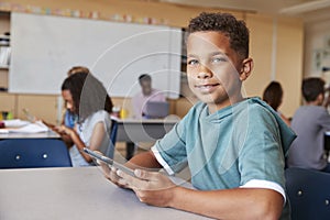 Boy using tablet in school class smiling to camera, close up