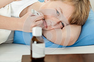 Boy using thermometer with medicine bottle nearby