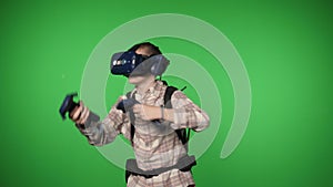 A boy using virtual reality glasses with controllers on a green background.