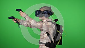 A boy using virtual reality glasses with controllers on a green background.
