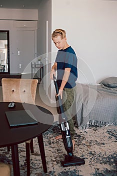 boy vacuum cleaning the carpet in the living room, modern interior. Busy, cleaning day. Home, housekeeping concept