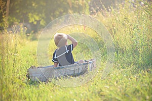 Boy in vintage sailor suit in boat on grass