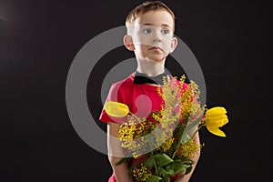 a boy with vitiligo in a red T-shirt with a bouquet of mimosa