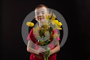 a boy with vitiligo in a red T-shirt with a bouquet of mimosa