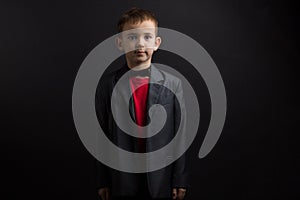 a boy with vitiligo in a red T-shirt, gray jacket, on black background