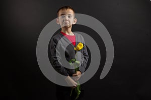 a boy with vitiligo in a red T-shirt, gray jacket, with a bouquet of yellow tulips