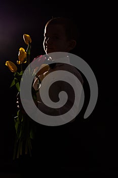 the boy with vitiligo in white shirt and a bow tie with tulips on a black Studio background