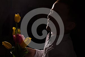 the boy with vitiligo in white shirt and a bow tie with tulips on a black Studio background