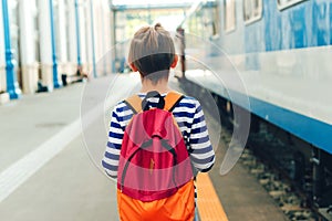 Boy waiting for express train on railway station platform. Kid with backpack on a subway