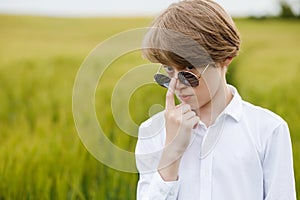 Boy walking with the american flag on the green wheat field celebrating national independence day. 4th of July concept