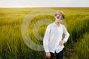 Boy walking with the american flag on the green wheat field celebrating national independence day. 4th of July concept