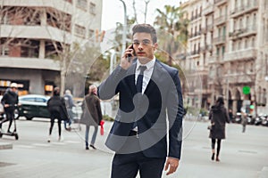 Boy walking with blue suit and calling by phone in city